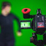 En VFX artist arbetar framför en green screen, fångad på kameraskärmen medan de skapar visuella effekter för film eller video.